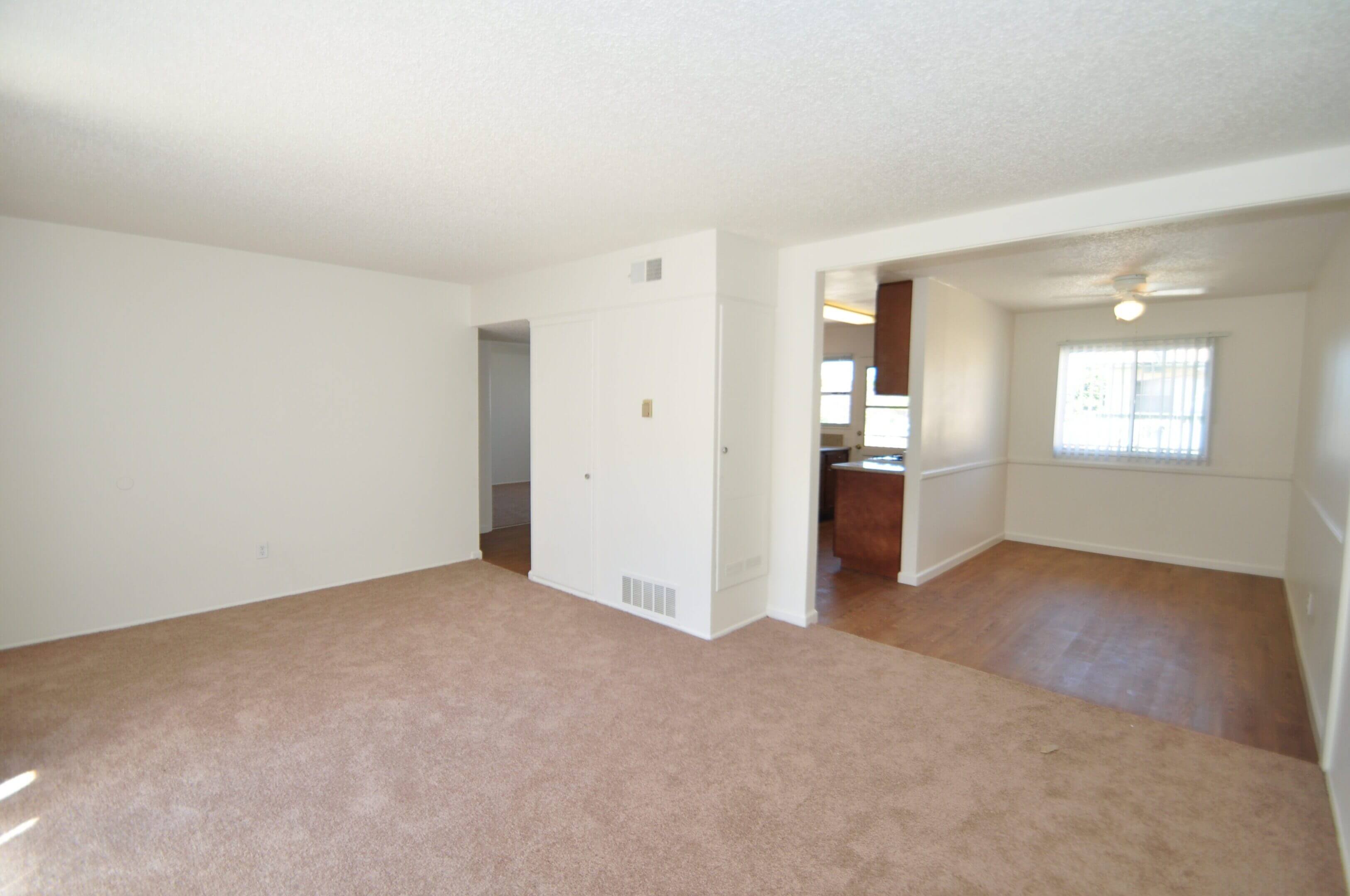 Empty carpeted living room with dining area